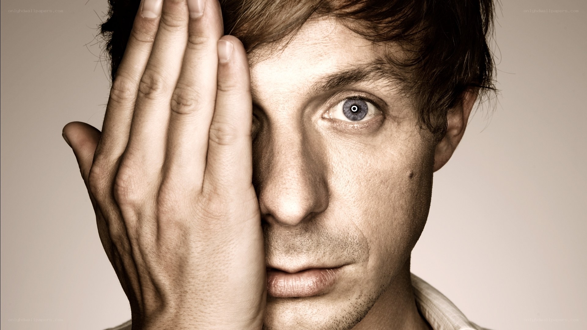 man covering one eye with hand