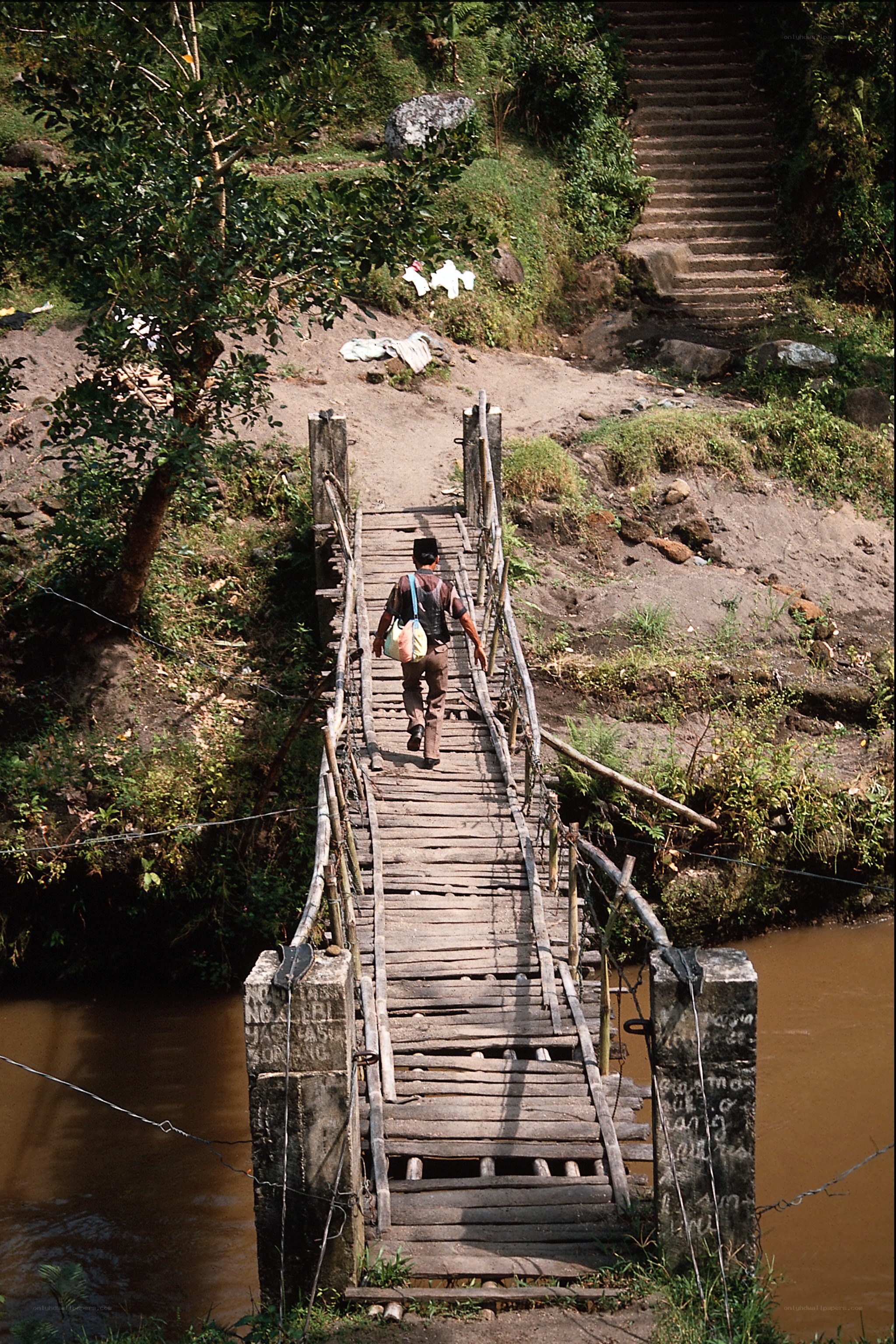 Man crossing wooden bridge