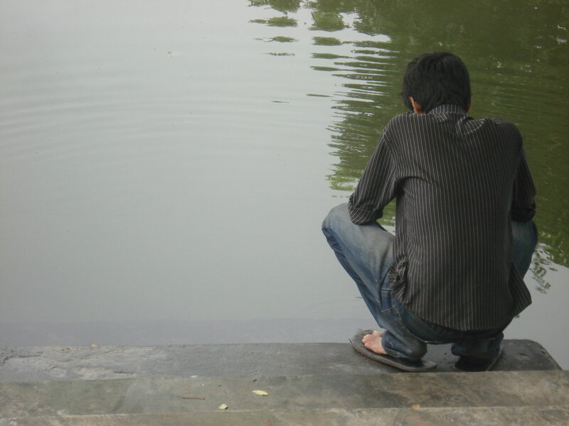 Man Crouching by Water