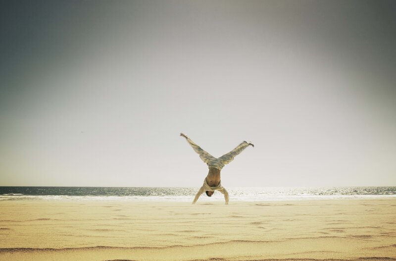 Man doing handstand on beach