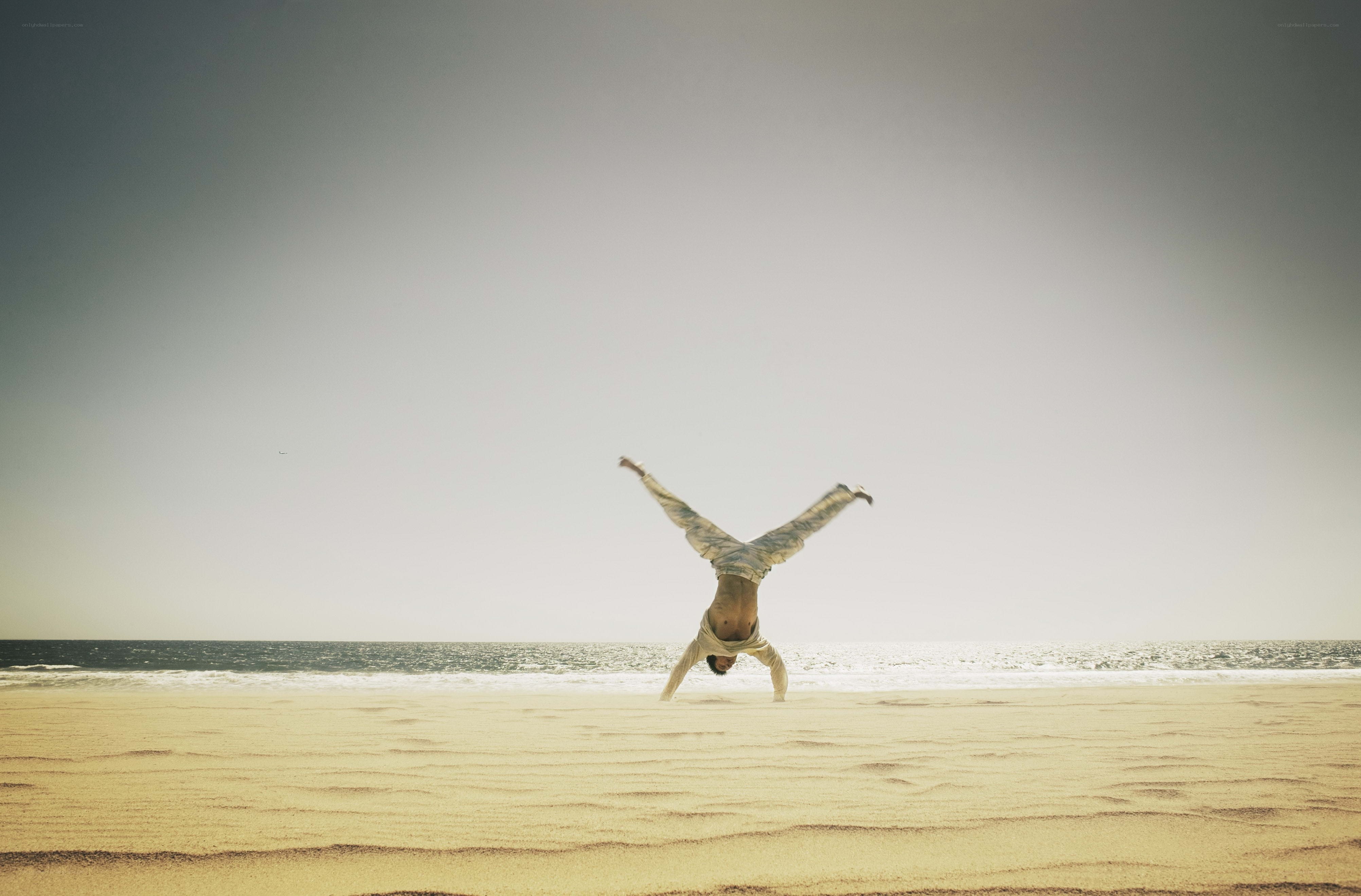 Man doing handstand on beach