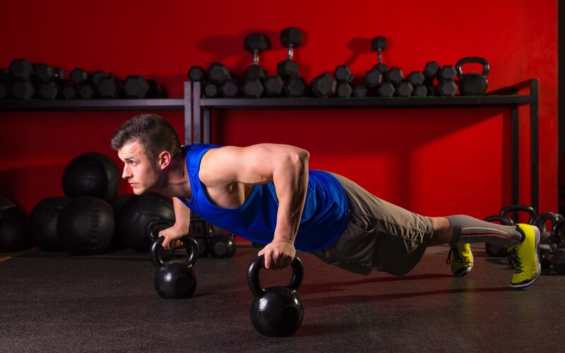 man doing push-ups with kettlebells