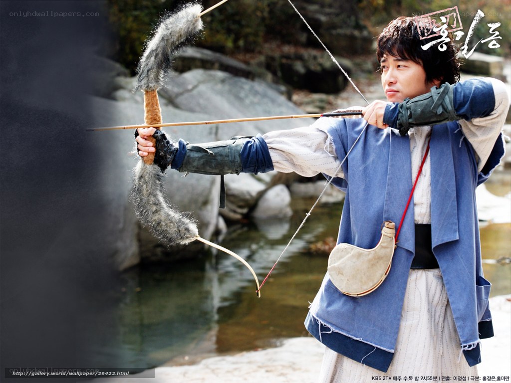 man drawing bow in traditional attire
