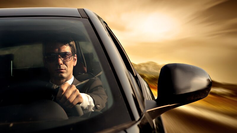 man driving car at sunset