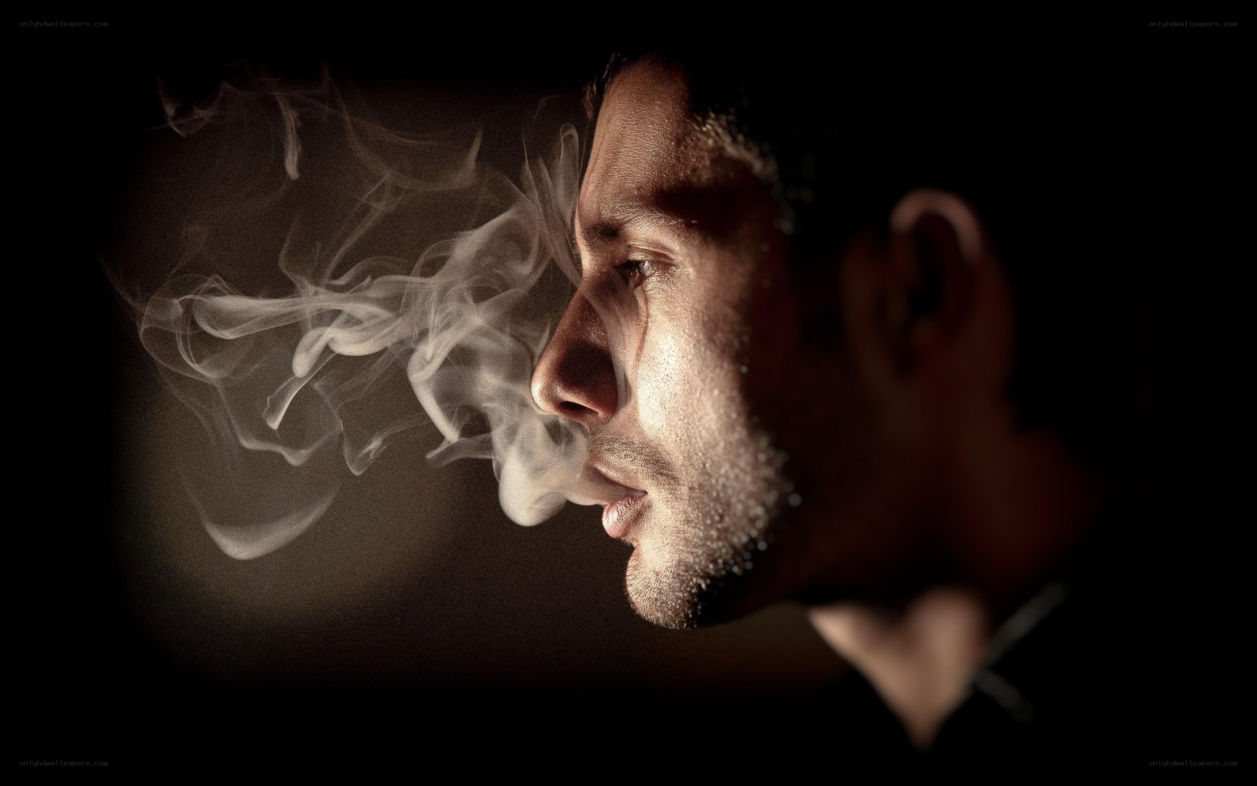 man exhaling smoke in profile