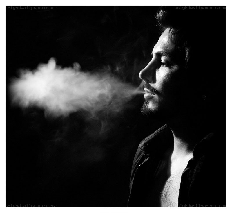 man exhaling smoke in profile