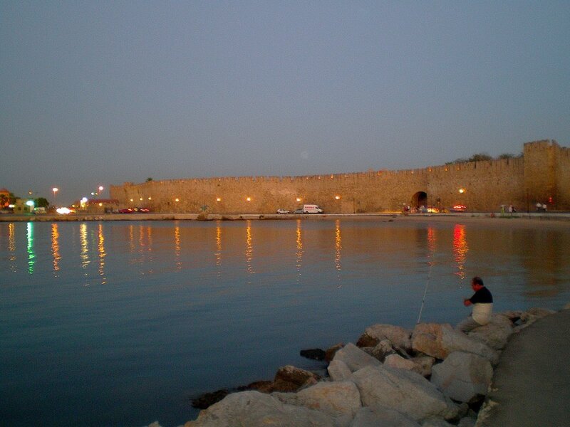 man fishing by ancient wall