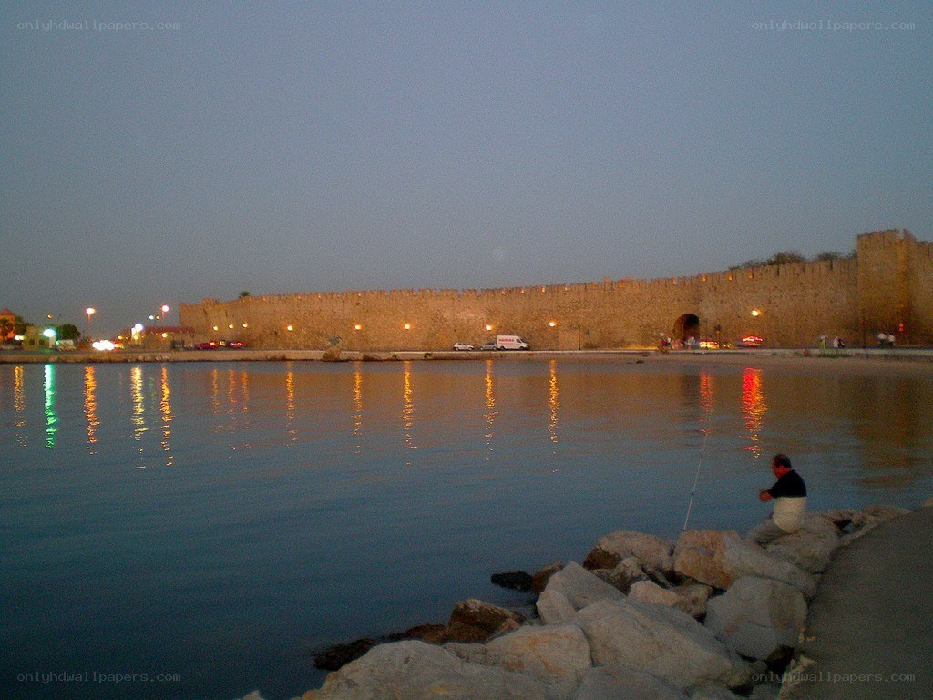 man fishing by ancient wall