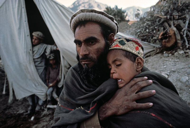 Man holding child in refugee camp