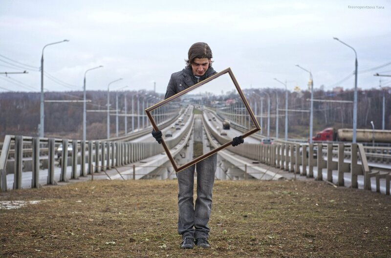 Man holding empty frame on bridge