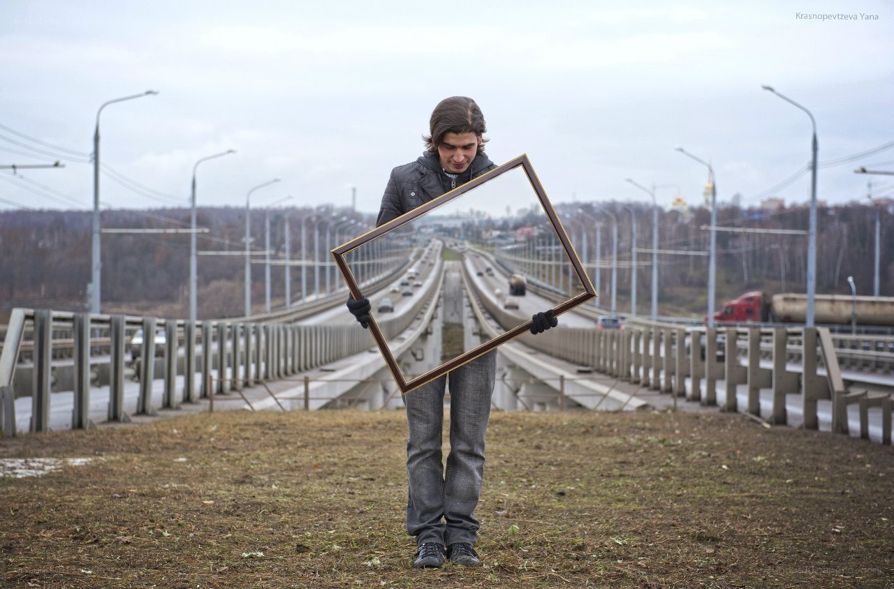 Man holding empty frame on bridge