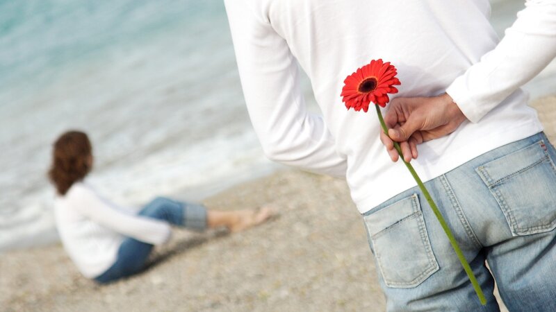 man holding flower behind back