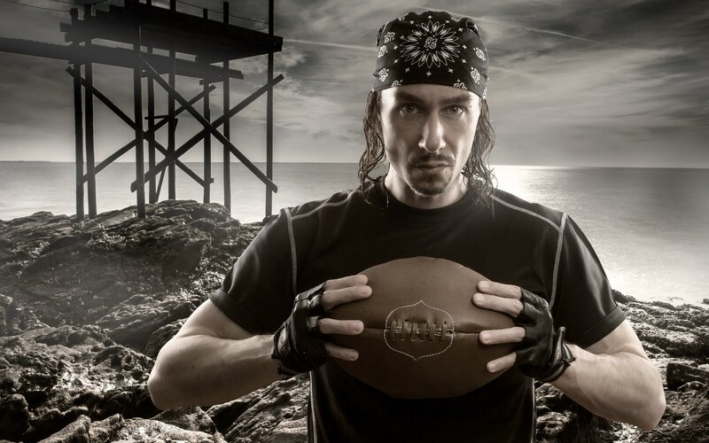 man holding football on beach