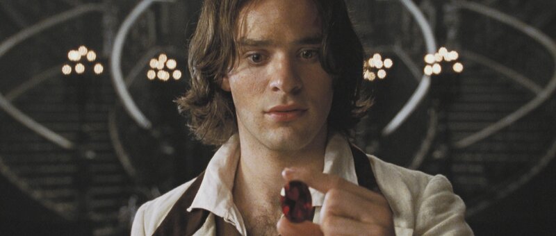 man holding red gemstone