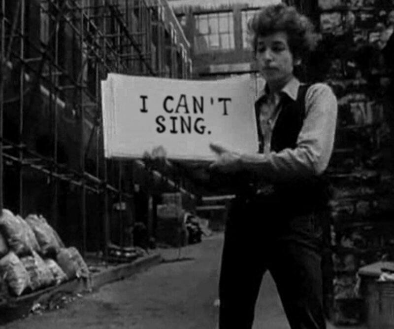 man holding sign that says i can't sing