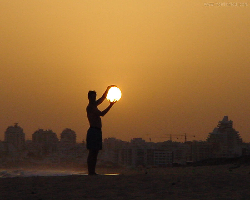 Man holding sun at sunset