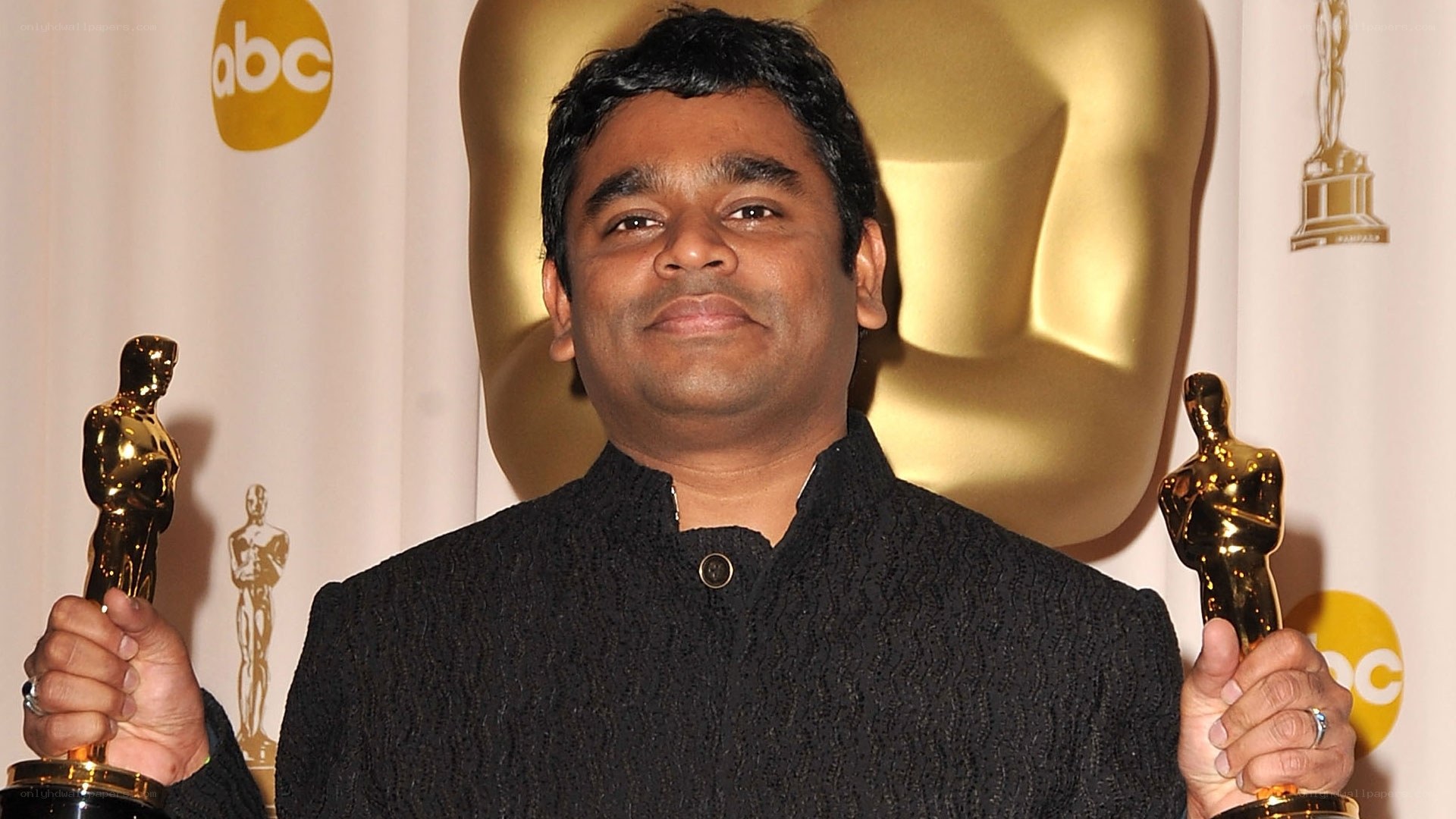 Man holding two Oscars