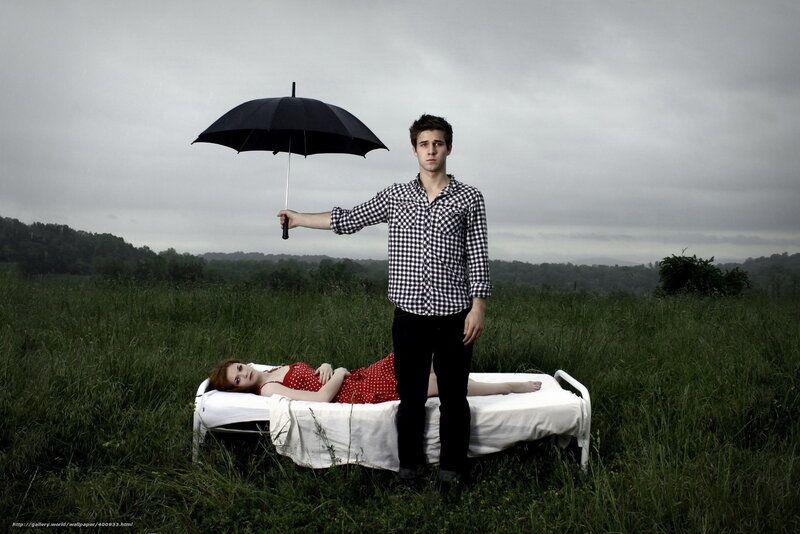 Man holding umbrella over woman