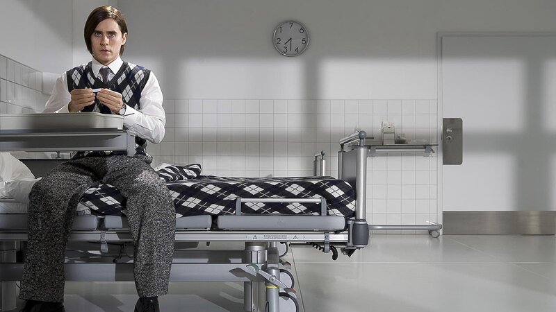 Man in argyle sweater on hospital bed