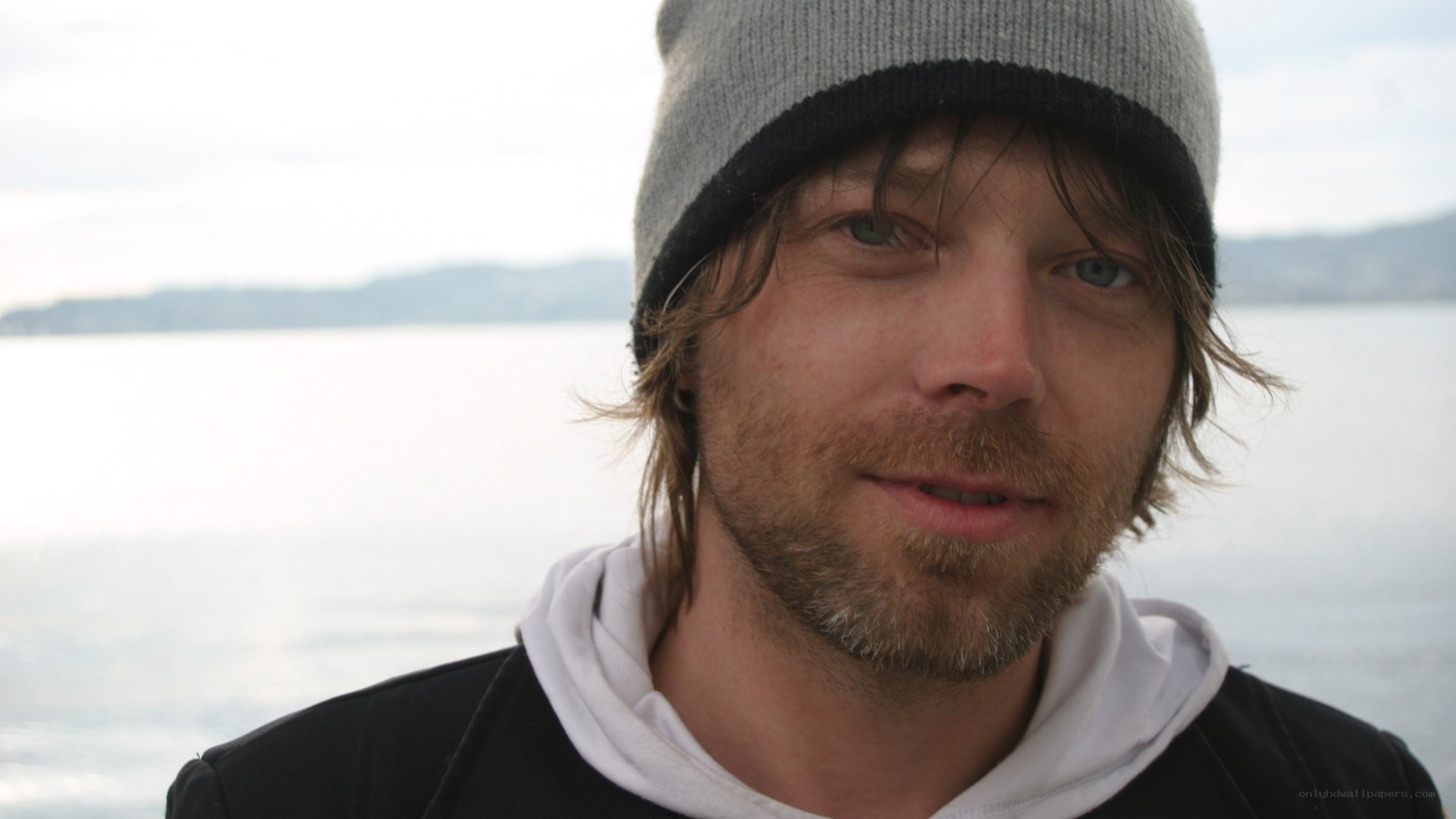 man in beanie by water