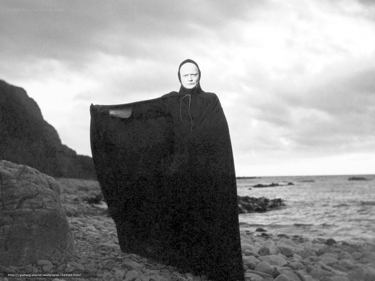 Man in black cloak on beach