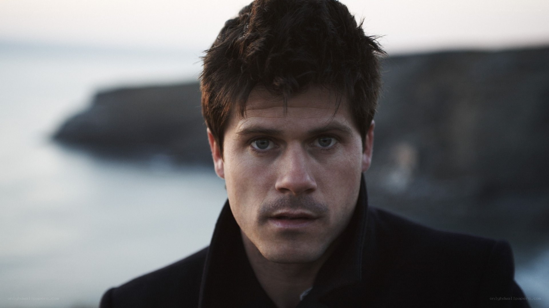 man in black coat by the sea
