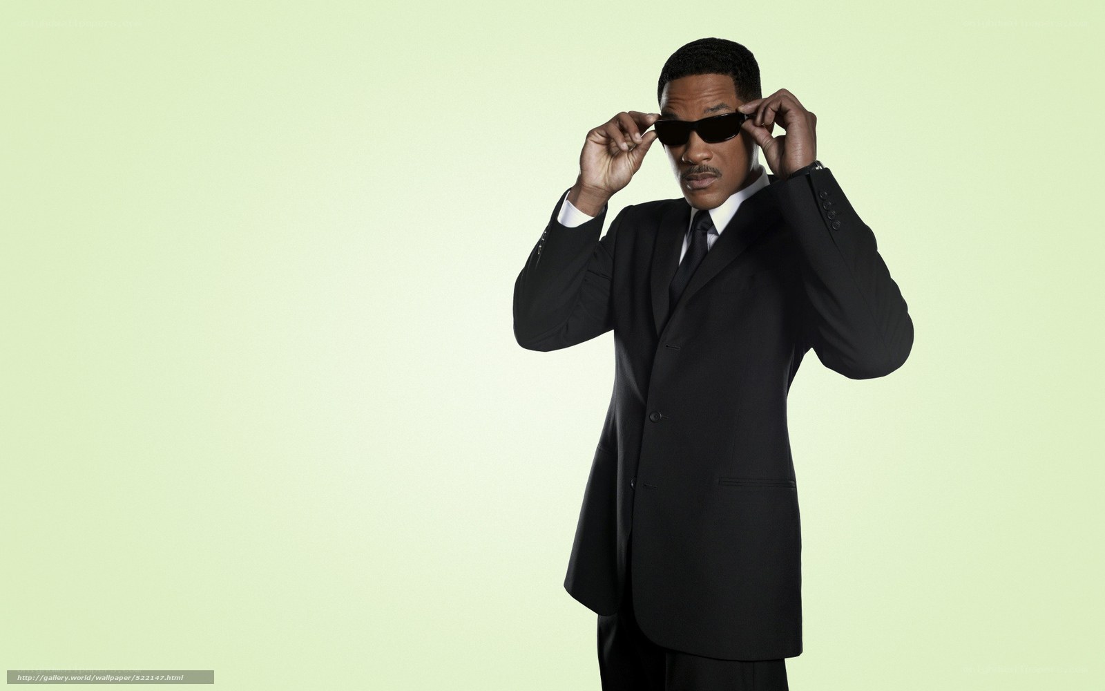 man in black suit adjusting sunglasses