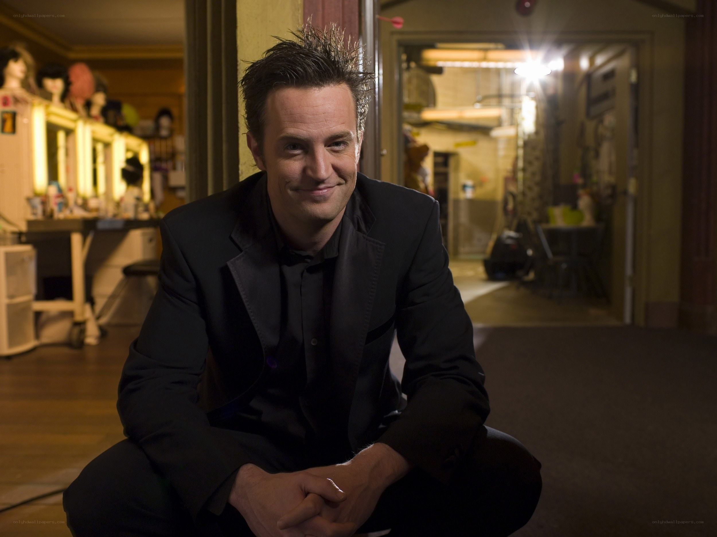 man in black suit crouching
