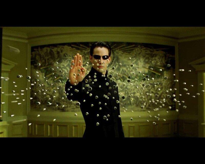 man in black suit stopping bullets