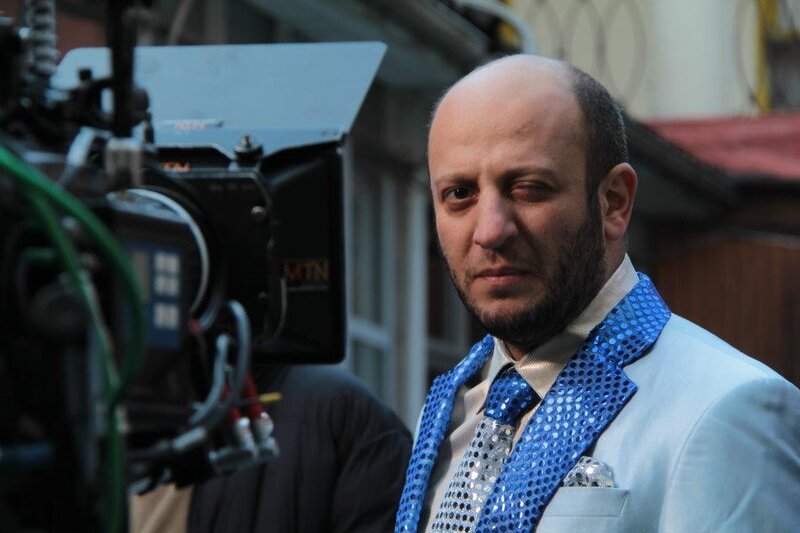 Man in blue sequined jacket on set