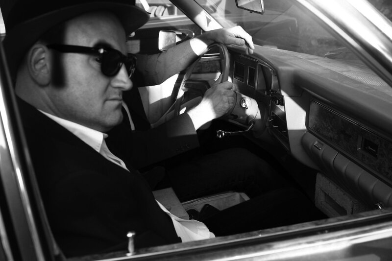 man in car wearing hat and sunglasses