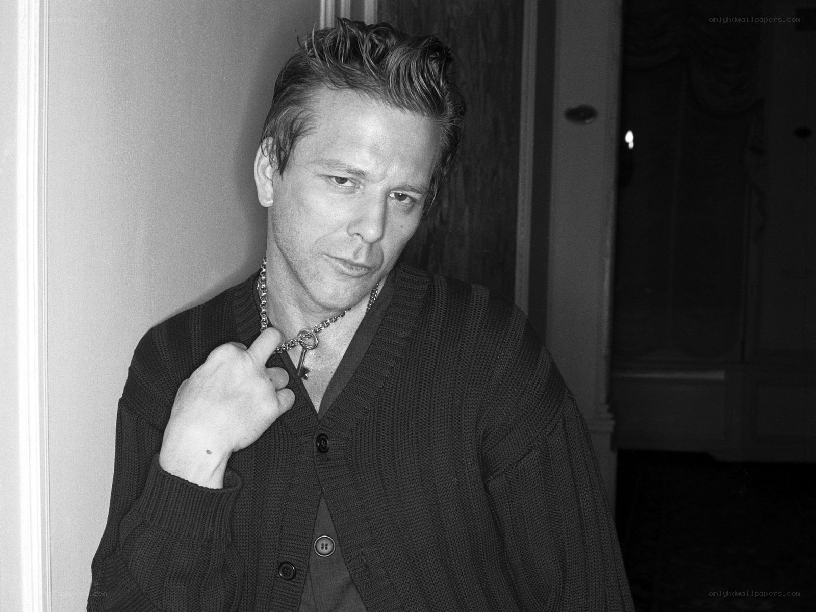 man in cardigan holding necklace
