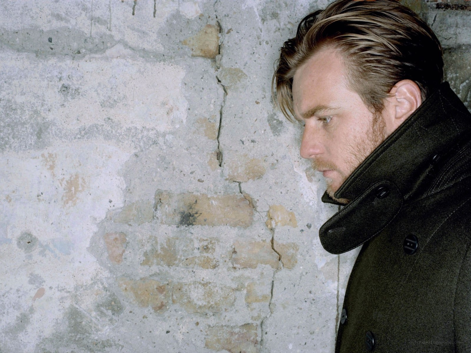 man in coat against brick wall
