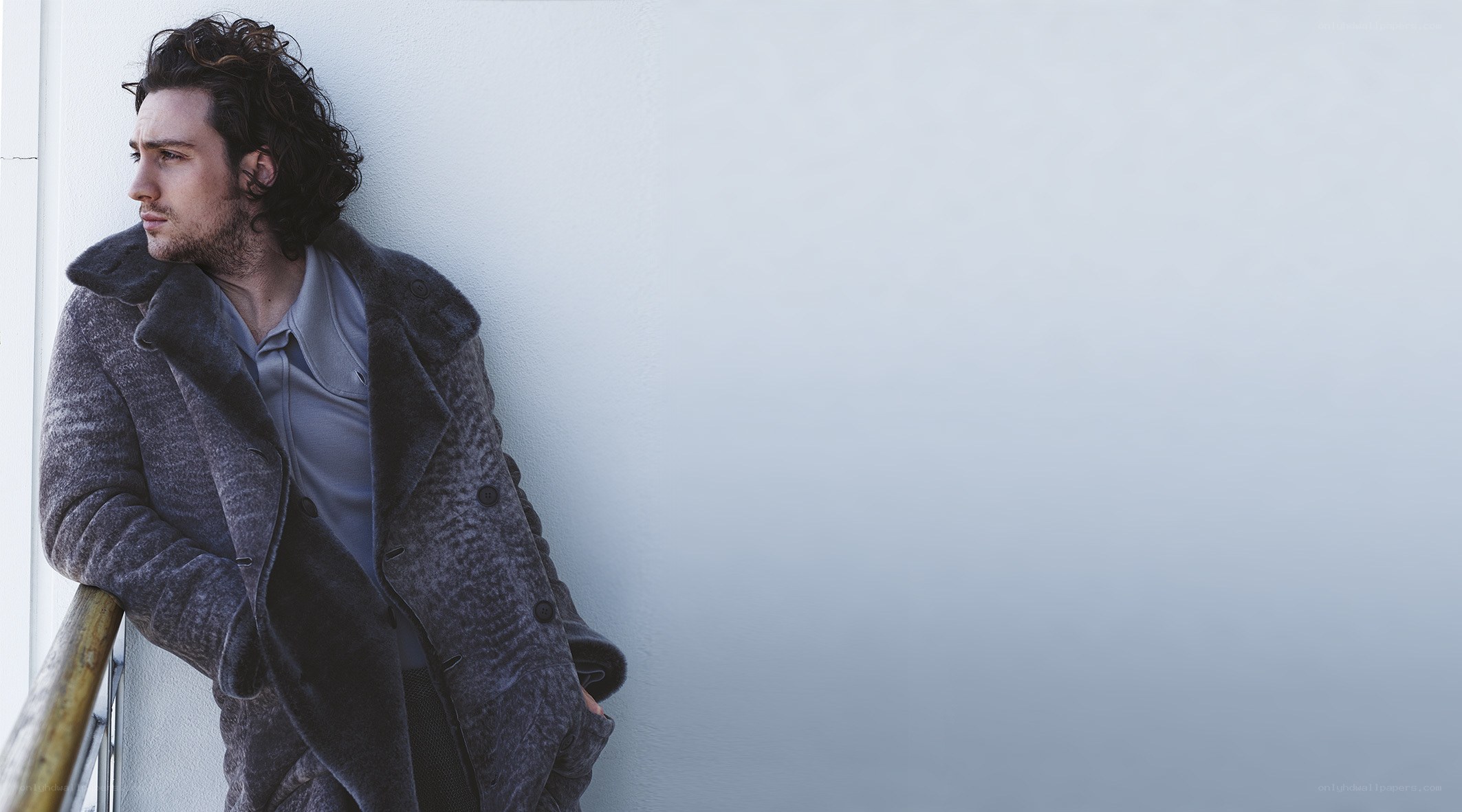 man in coat leaning on wall
