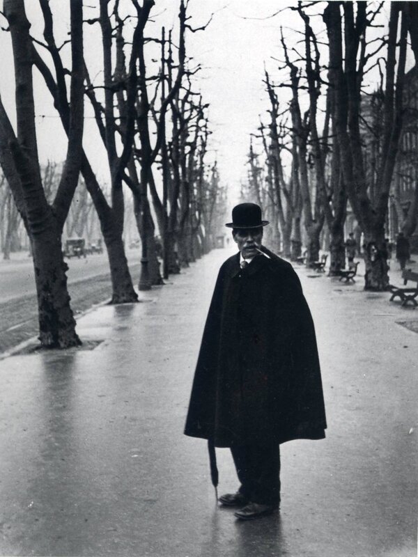 Man in coat on a tree-lined street