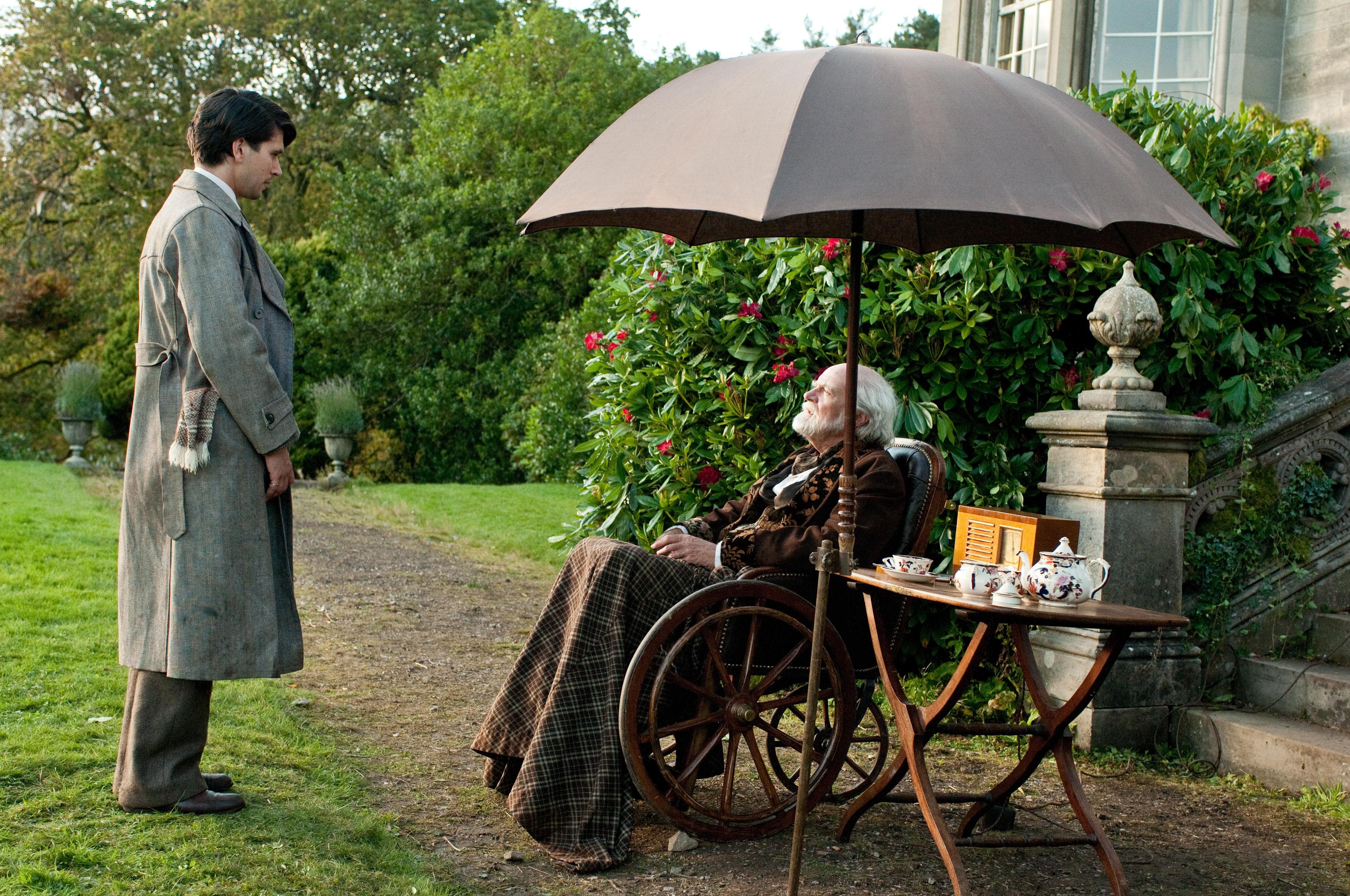 Man in coat speaking to elderly man
