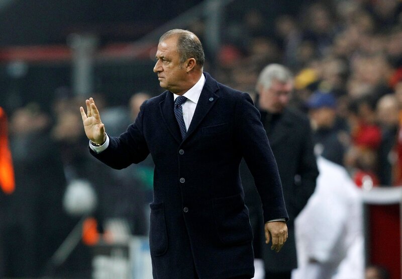 Man in coat waving at stadium