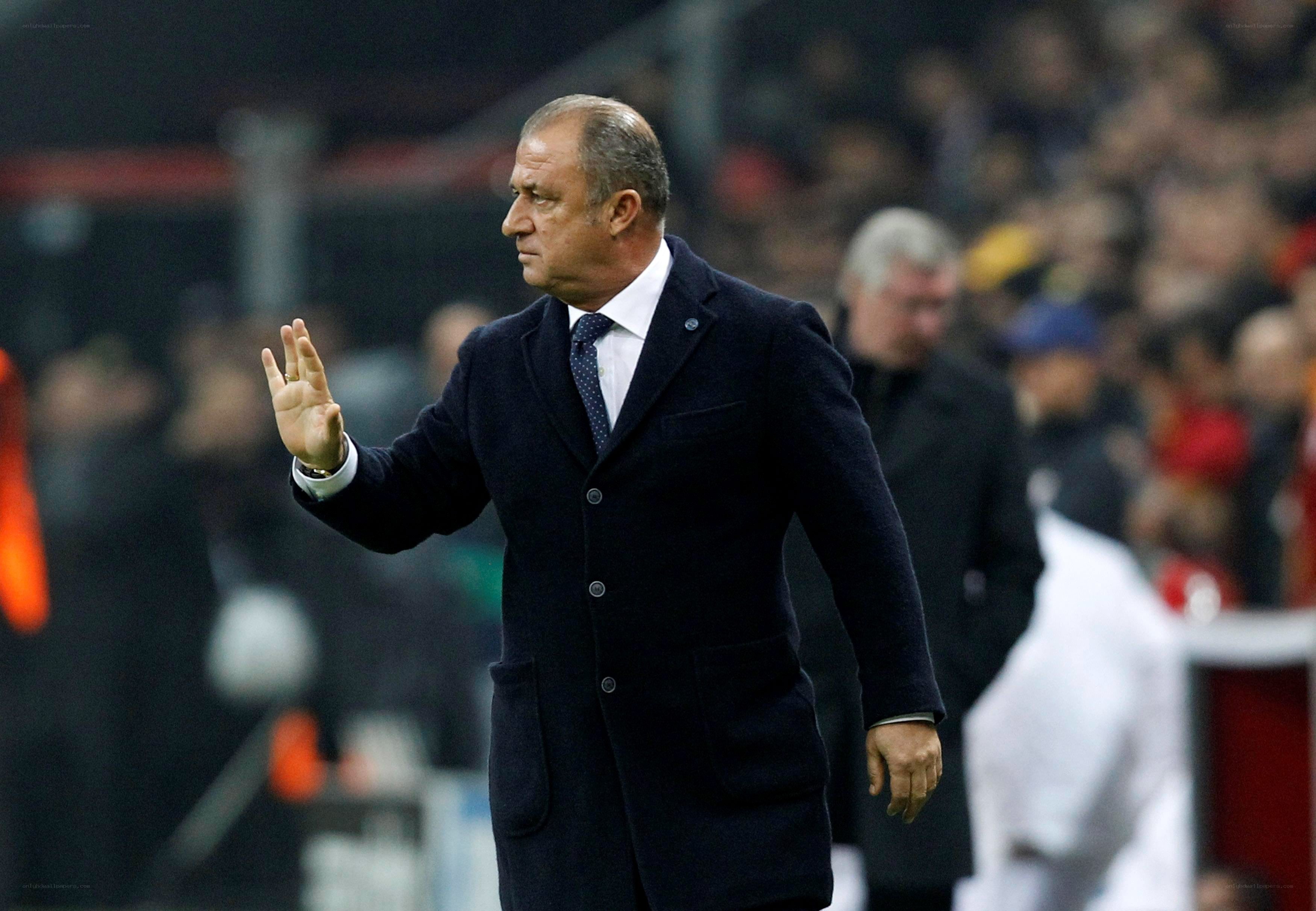 Man in coat waving at stadium