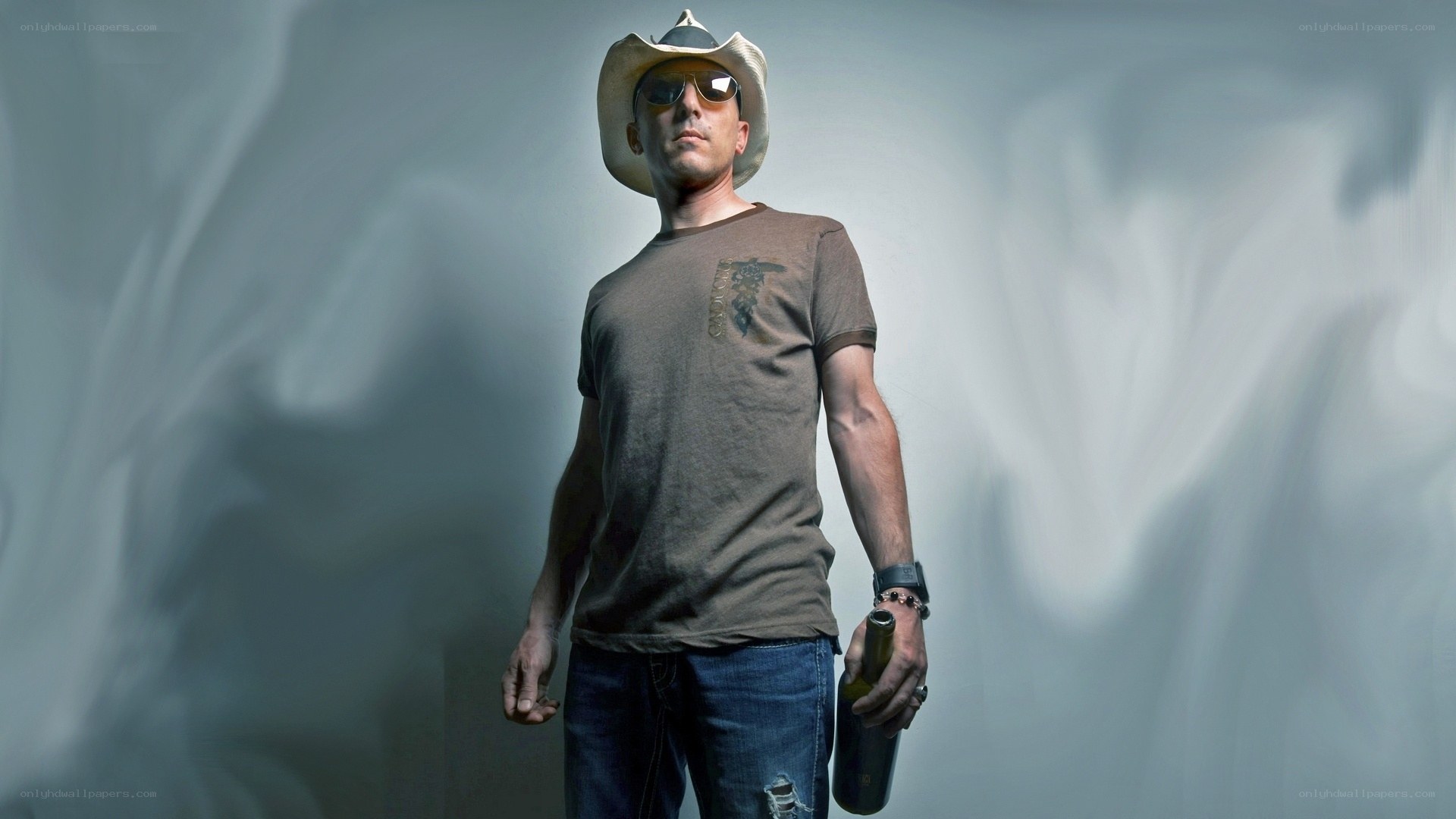 man in cowboy hat holding bottle