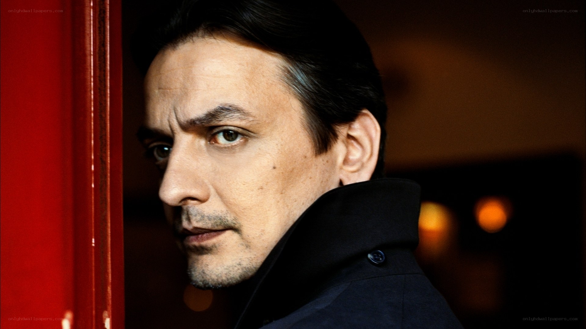 man in dark coat looking over shoulder
