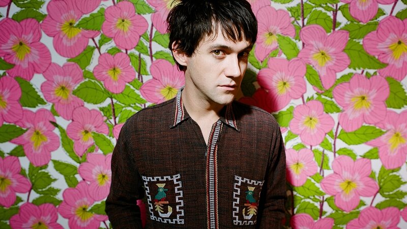 man in front of floral wallpaper