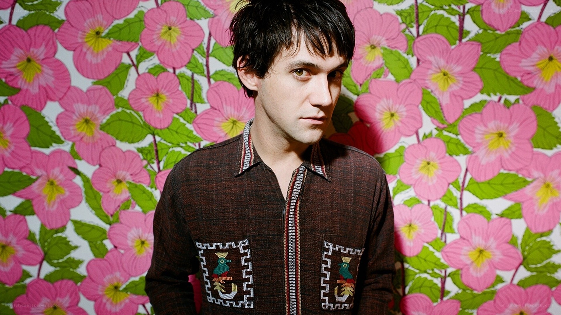 man in front of floral wallpaper