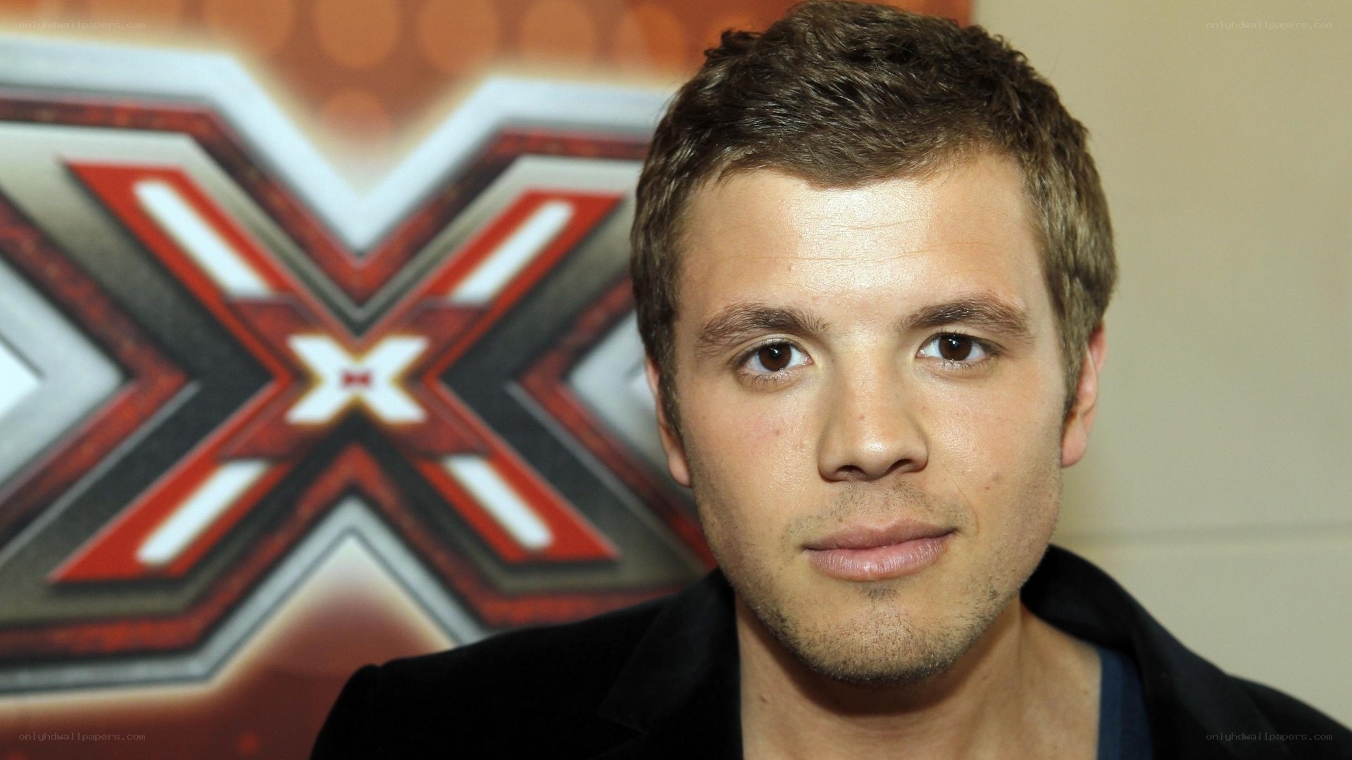 man in front of x factor logo