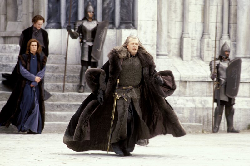 Man in fur coat walks through courtyard