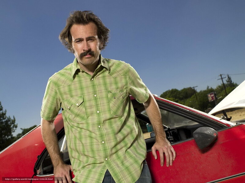 man in green shirt by red car