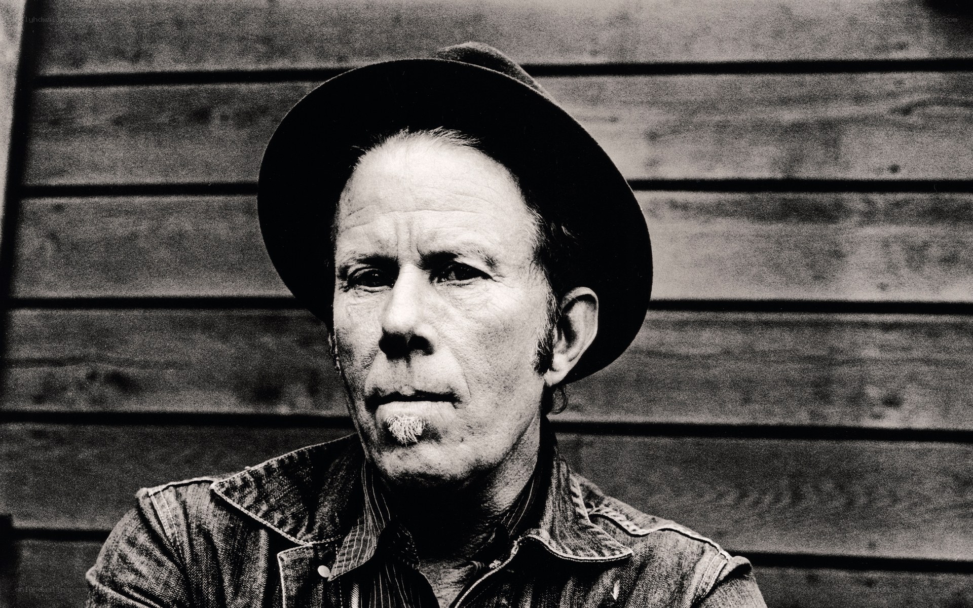 man in hat against wood wall