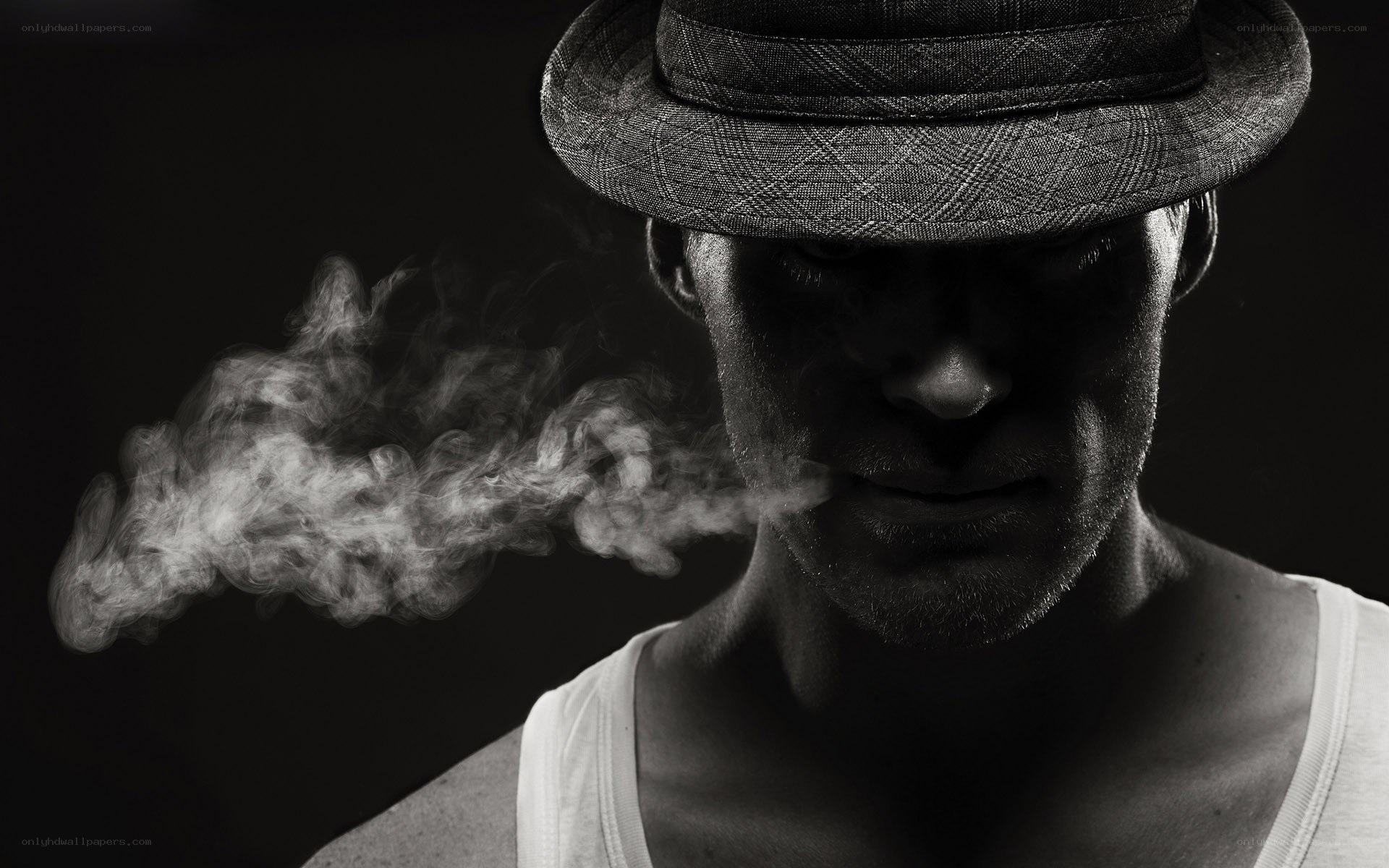 man in hat exhaling smoke