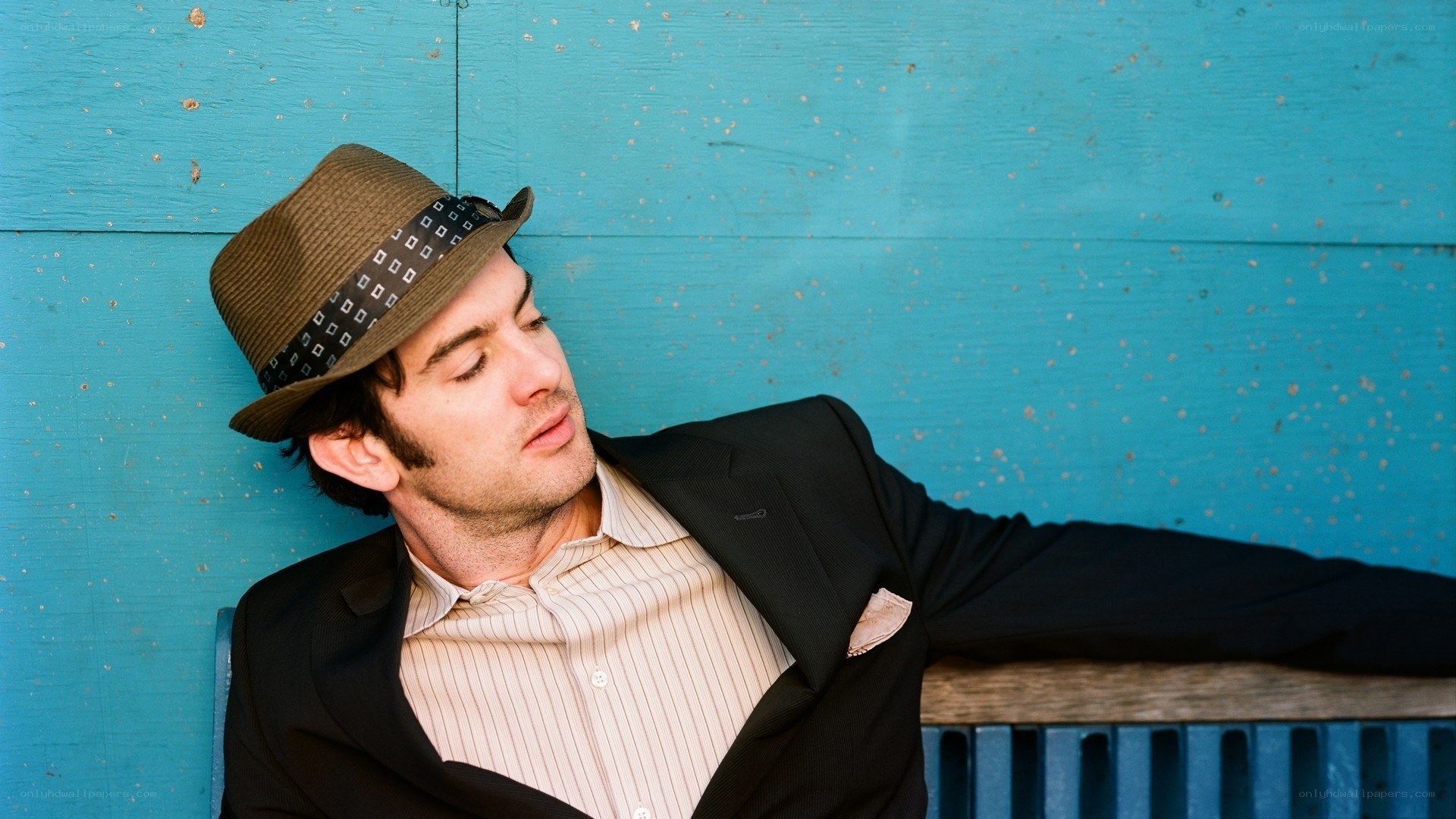 man in hat leaning against wall