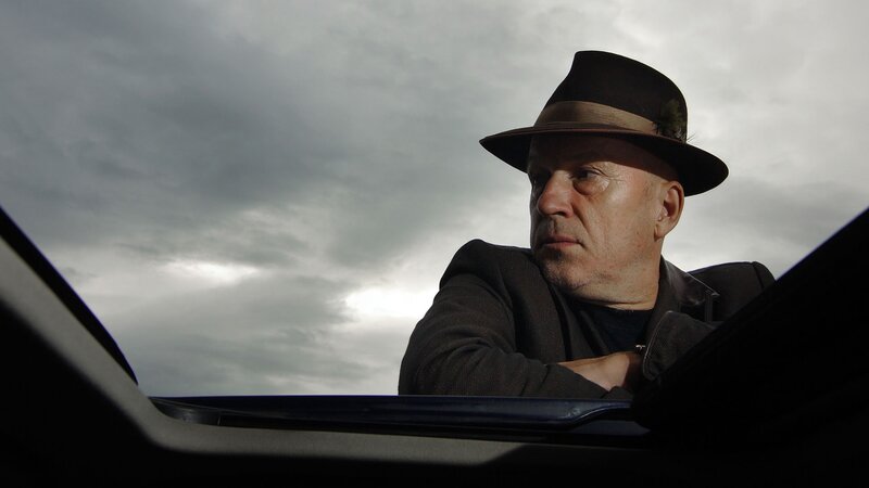 Man in hat looking out car window