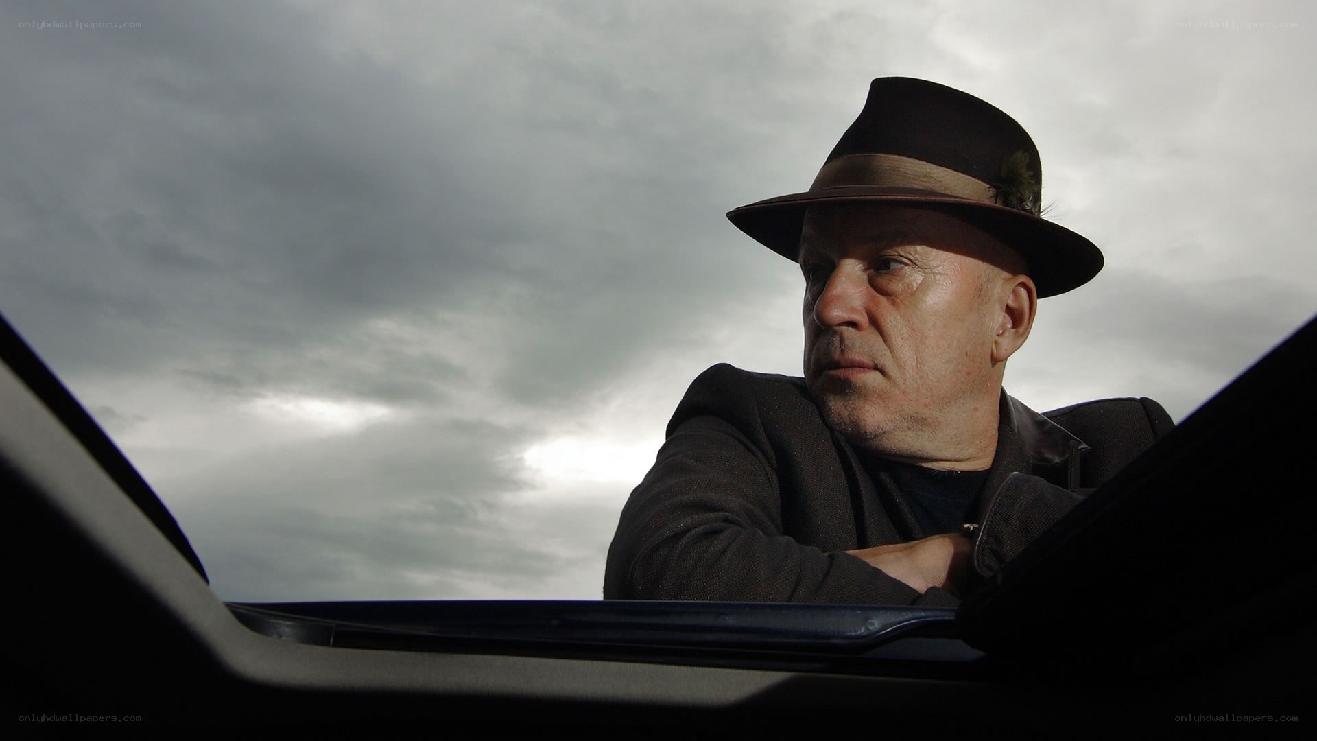 Man in hat looking out car window